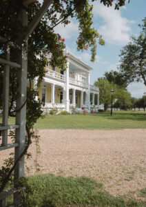 Viewed from the floral trellis, The Taylor Mansion is viewed with its bright canary-yellow facade.